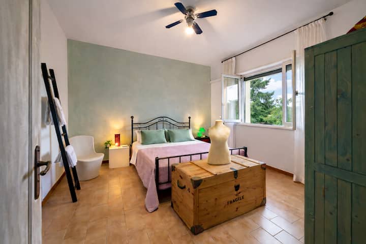 Habitación doble luminosa con una cama grande y cómoda, colores cálidos y un ambiente relajante. La ventana deja entrar mucha luz natural. Ideal para parejas o viajeros que buscan tranquilidad y comodidad después de un día en la playa.