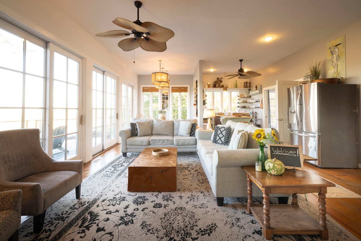 منطقة غرفة المعيشة تطل على منطقة الطعام والمطبخ. يحتوي على 3 أبواب منزلقة كبيرة تفتح على السطح الكبير المطل على المستنقع