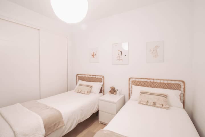 Chumba cha watoto chenye mwanga na kinachofaa kwa matumizi na vitanda viwili vidogo na kabati lililojengwa ndani.