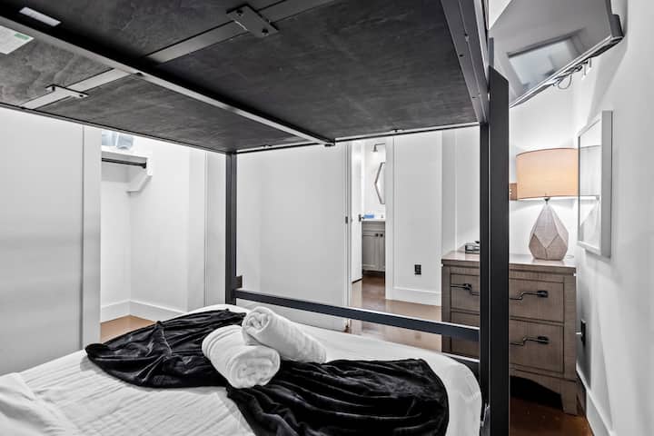 Custom black metal framed bunk bed setup with rolled towels and a view into the hallway.