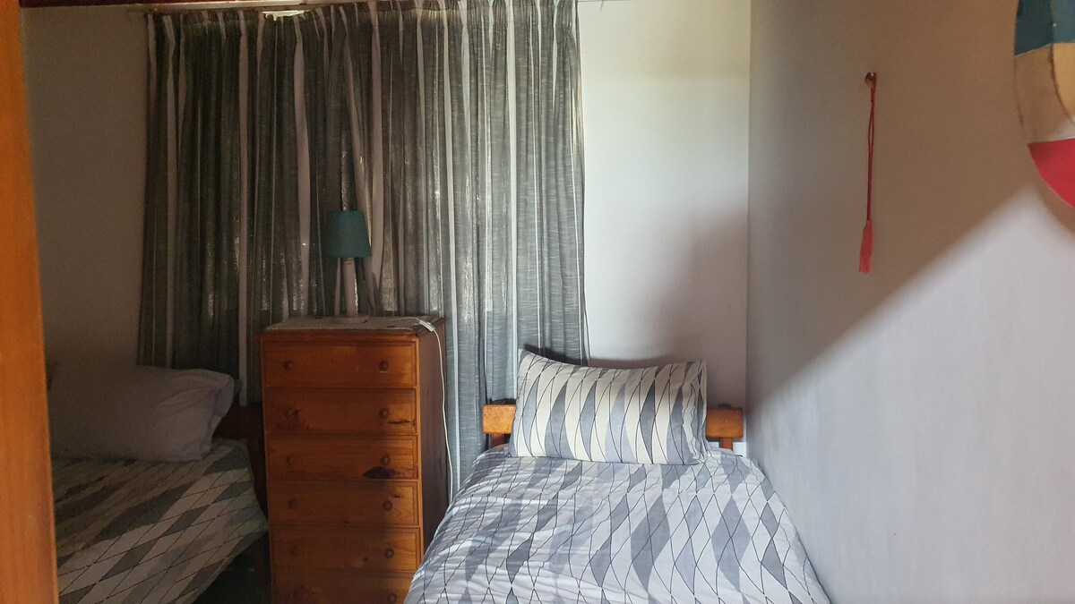 Така снимката показва двете единични легла с скрин и спуснати завеси