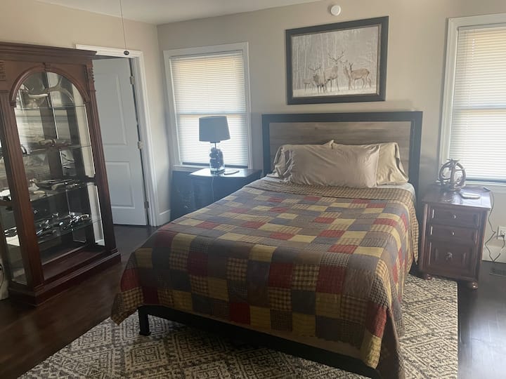 Enorme dormitorio principal con zona de estar, sillón reclinable, chimenea, televisión de pantalla plana y sonido envolvente.