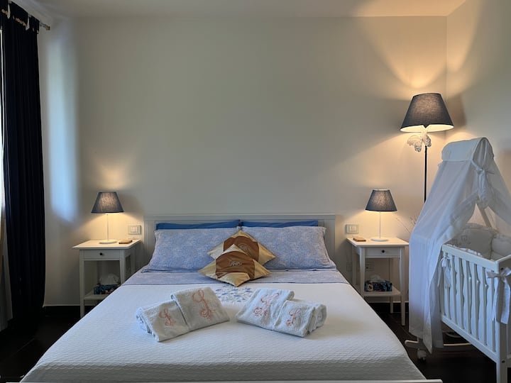 Camera da letto matrimoniale con cabina armadio, culla.

Double bedroom with walk-in closet, cot bed.