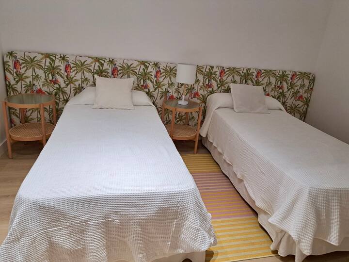 Dva kreveta za jednu osobu s ogledalom i ormarom.