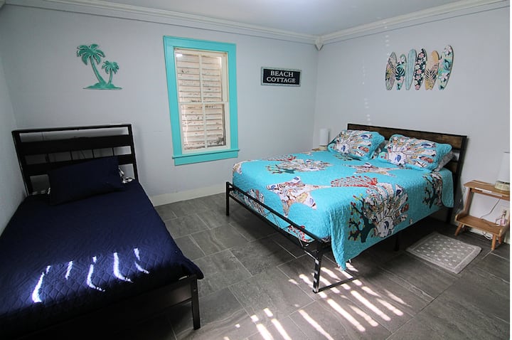 Bright beach-themed bedroom with queen and twin beds for flexible stays