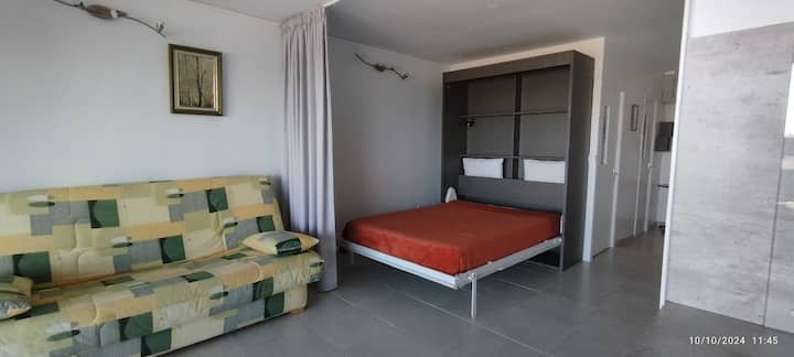 Dormitorio cama armario y sofá cama, separados por una gran cortina opaca