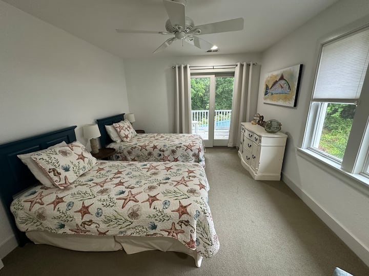 בחדר השינה בקומה השנייה יש שתי מיטות נפרדות ומרפסת משותפת בחוץ.