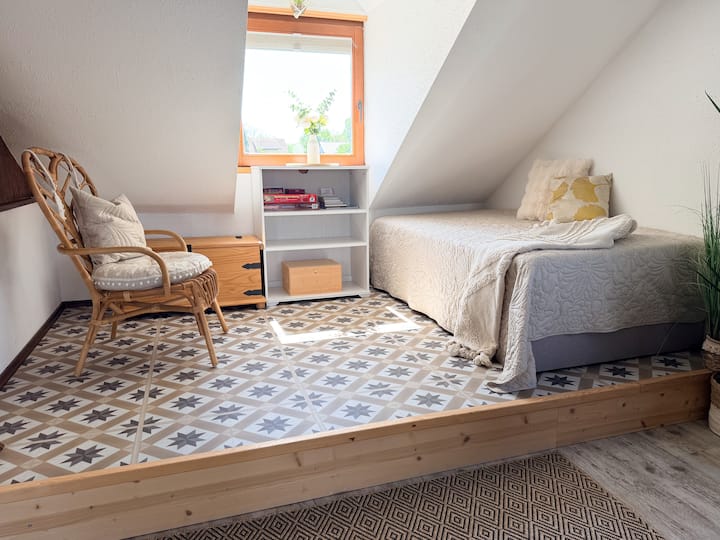 Das Boxspringbett 1,00 x 2,00m im Wohnzimmer (klimatisiert) liegt auf einem erhöhten Podest unter einer Dachschräge (eingeschränkte
Stehhöhe).