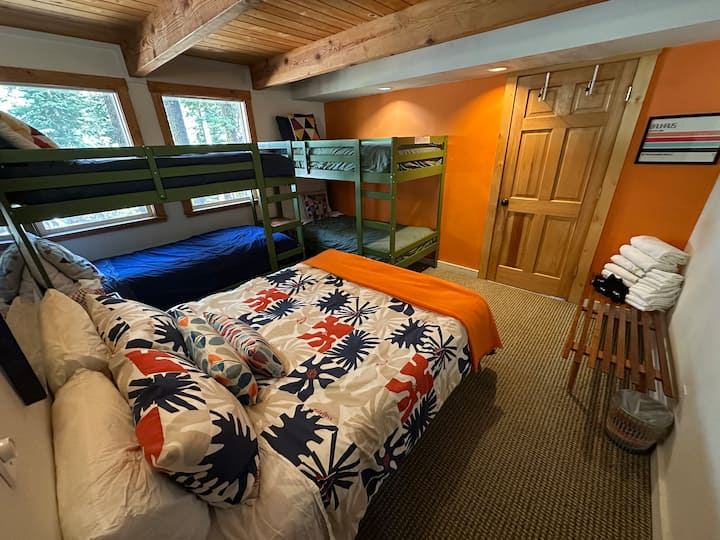 Orange room. New mattresses and bedding. Down pillows and comforters, queen bed, two bunk beds, each with two single beds. Dart board, games and toys, bench for luggage, heat / AC. 