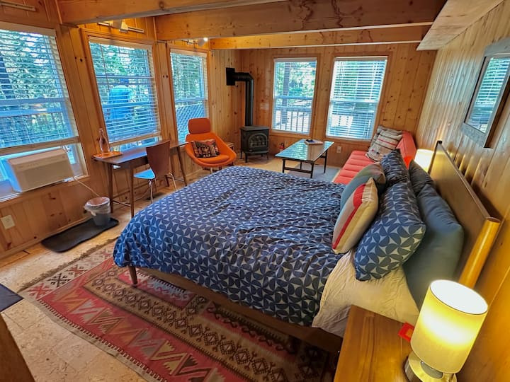 Primary Bedroom: En suite full bathroom, gas woodstove, new queen mattress and bedding, full sized sleeper sofa (shown in sofa position), down pillows and comforter, desk and chair, lounge chair, luggage rack, coffee table, heat / AC.