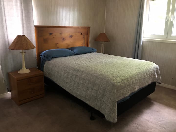 Dormitorio principal con cama tamaño Queen y medio baño.
