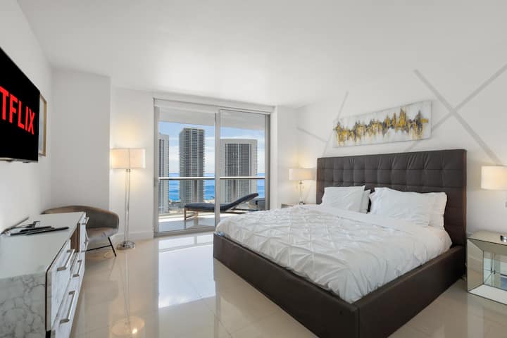 Entra en el dormitorio principal, donde una cama tamaño king, una decoración elegante y ventanas del suelo al techo con vistas al mar crean un refugio sereno. Disfruta de la comodidad de tener un baño en tu habitación.