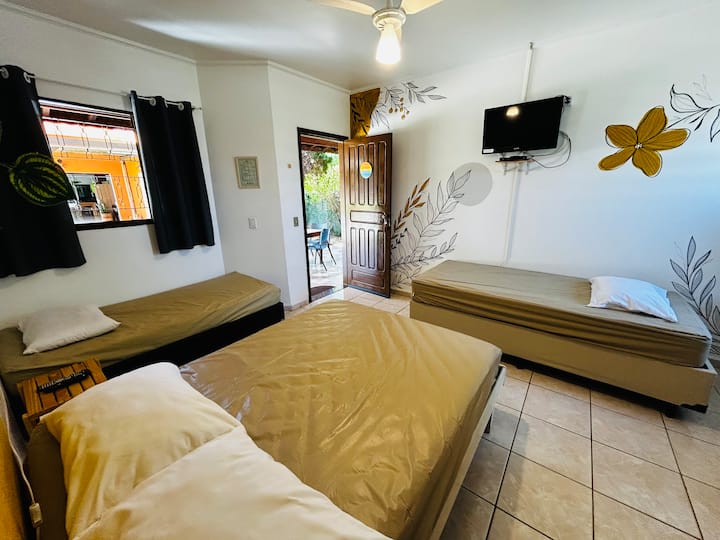 Quarto com 1 cama de casal padrão, 1 cama de solteiro tamanho padrão e 1 cama de solteiro king (solteirão). TV, ventilador de teto + ventilador de bancada e frigobar