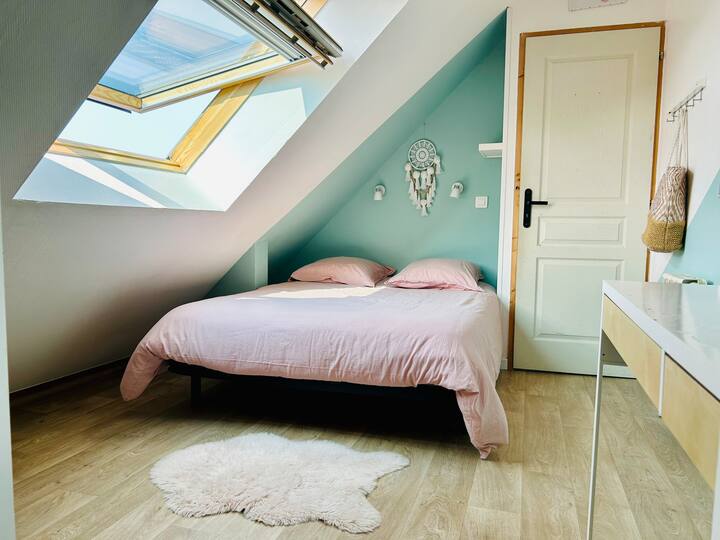 Habitación abuhardillada luminosa con cama doble, tocador y espacio de almacenamiento. Fresco en verano gracias al aire acondicionado en la entreplanta contigua.