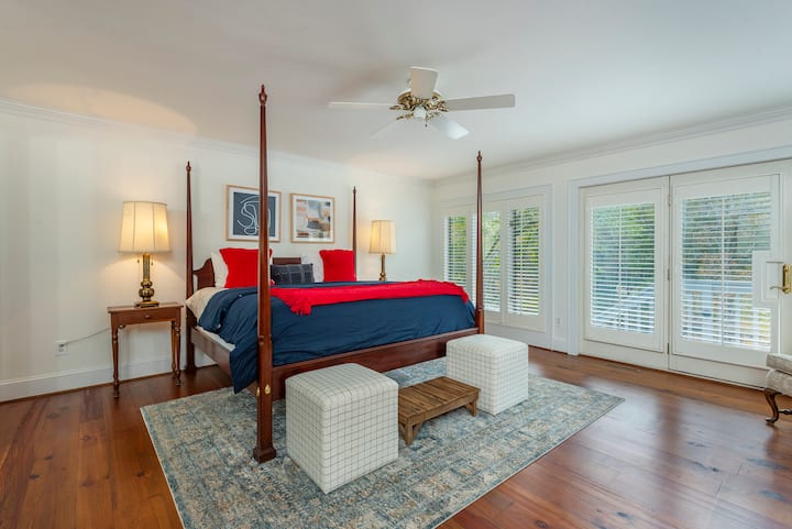 First-floor master bedroom with ensuite bathroom, king-size bed, walk-in closet, bathtub, walk-in shower, dual sinks, and glass door leading to the balcony