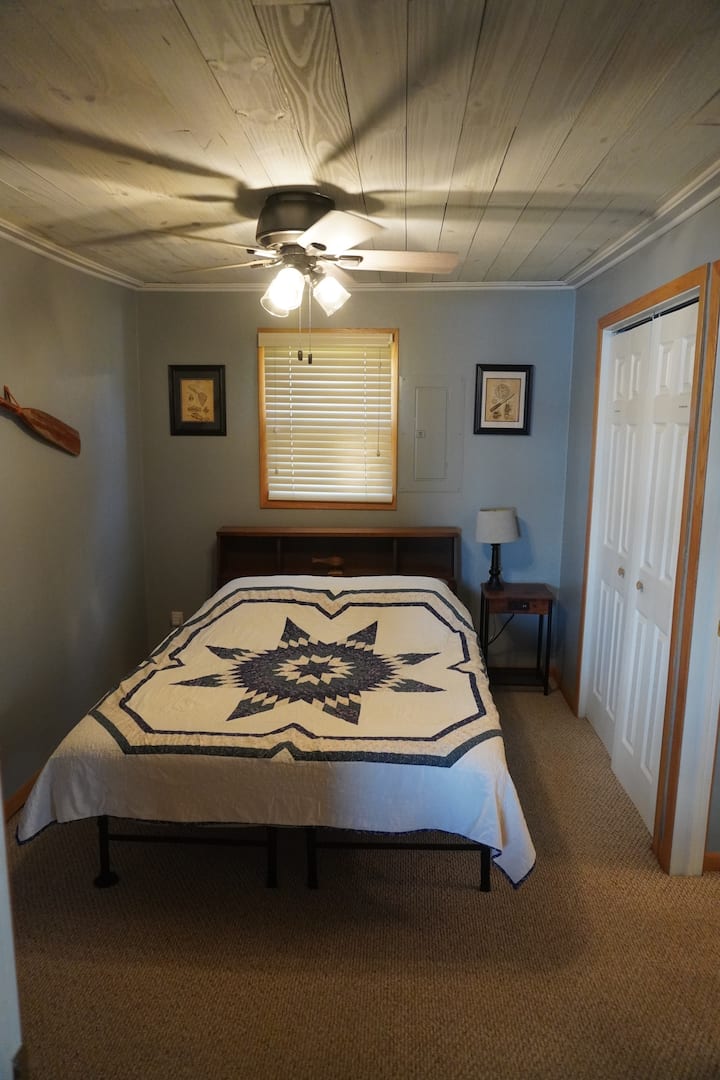 Dormitorio principal con cama tamaño queen, una mesita de noche con puerto USB y baño adjunto de tres cuartos.