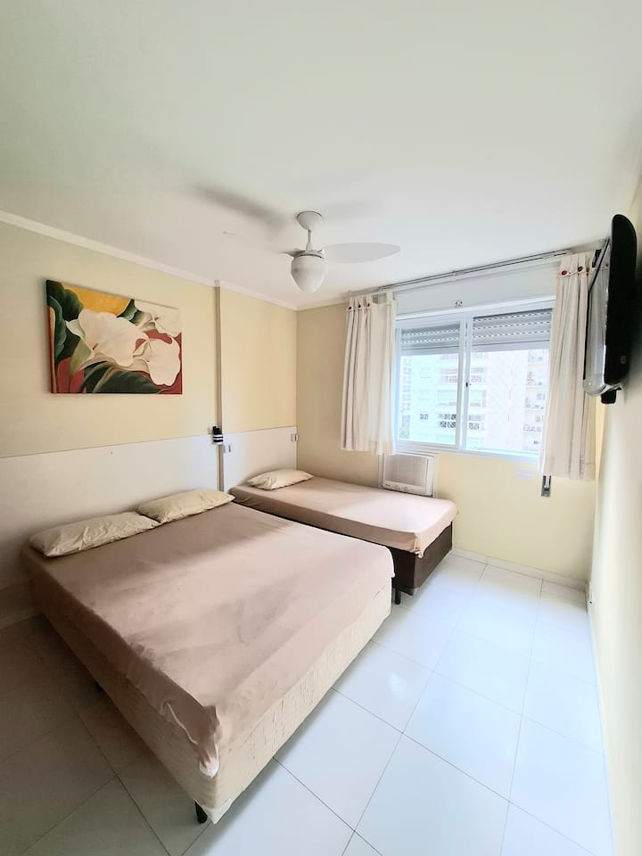 卧室2，配备1张双人床和1张单人床、电视、空调、风扇和窗户上的屏风