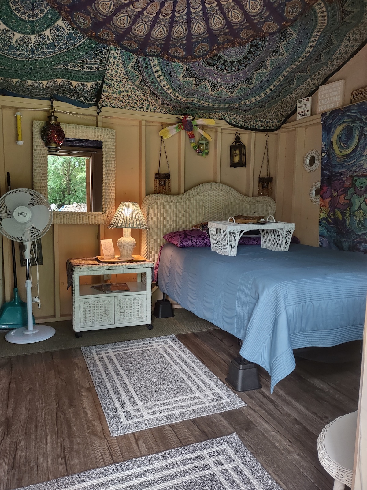 Tämä on näkymä The Grateful Shediin. Täysikokoinen sänky ja sen alla täysikokoinen kokoontaitettava futonpatja. Valkoisessa pajuyöpöydässä on hiustenkuivaaja ja silitysrauta. Herää tanssiviin karhuihin ja höyhenpeitteisten ystävien suloisiin lauluihin❤️