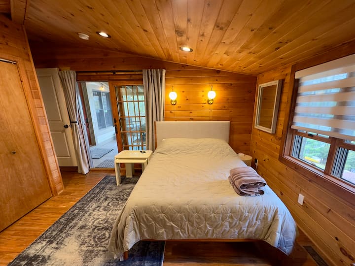 Cozy wood-paneled bedroom with porch access, natural light, and comfy linens