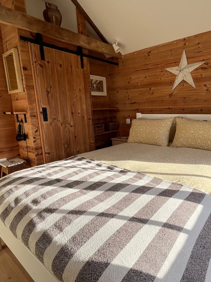 غرفة نوم ذا بارن مع سرير بمقاس كبير وخزانة ملابس ومجفف شعر. 