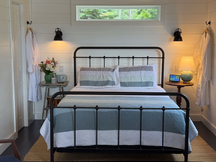 Egy hangulatos, nagy franciaágy, paplanok, köntösök és olvasólámpák a fő hálószobában, kilátással az öbölre.