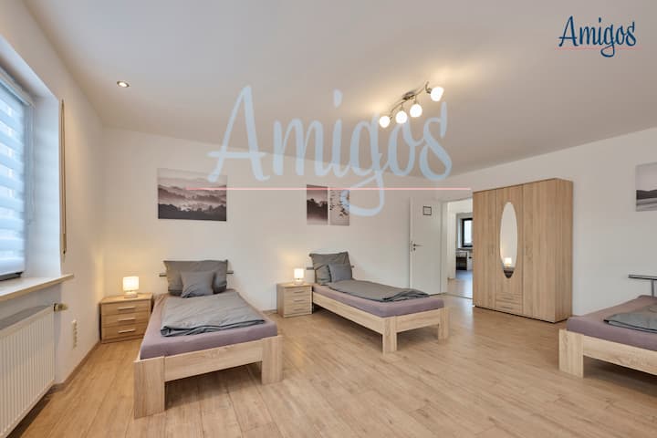 Chumba cha kisasa kilicho na vitanda vitatu vya mtu mmoja, meza za kando ya kitanda na mapambo mazuri. Ubunifu wa ndani wenye nafasi kubwa hutoa starehe na mtindo, unaofaa kwa familia au makundi ambayo yanathamini mazingira ya starehe.