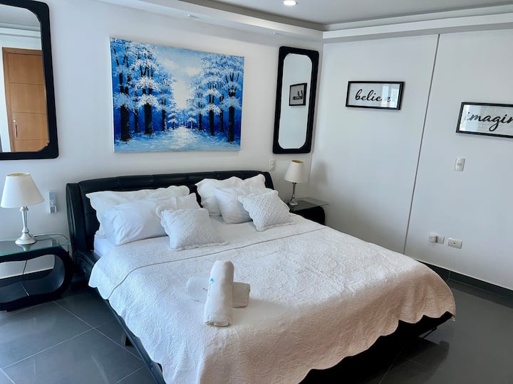 Master bedroom suite featuring a king-size bed, crisp white linens, and serene statement art for a peaceful night's sleep.