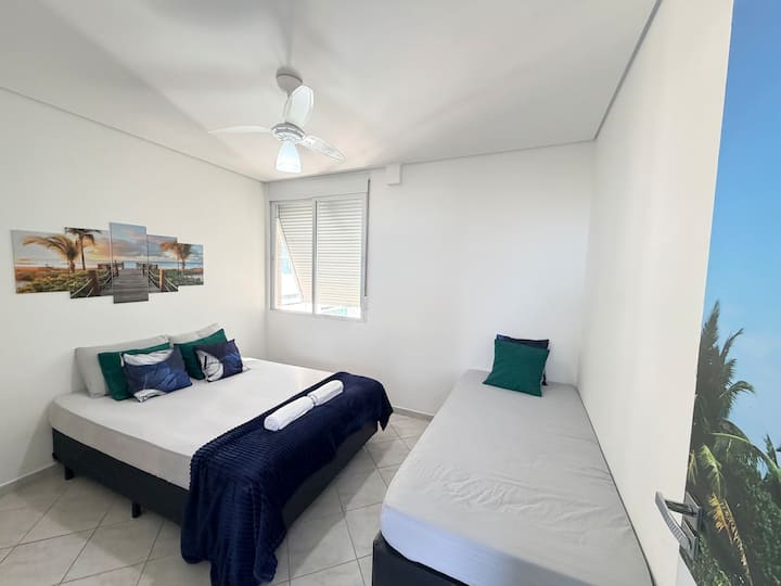 Segundo quarto com cama de casal, cama de solteiro ambiente espaçoso.