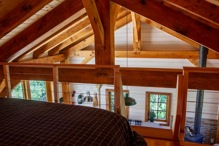 Sleeping loft looks down over the main sitting room and timber frame joinery.