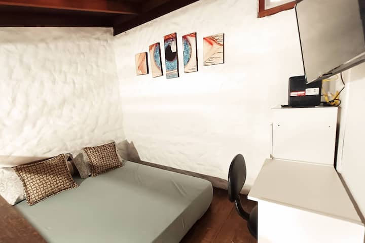 mezanino com cama Queen, TV, cômoda e mesa de trabalho.