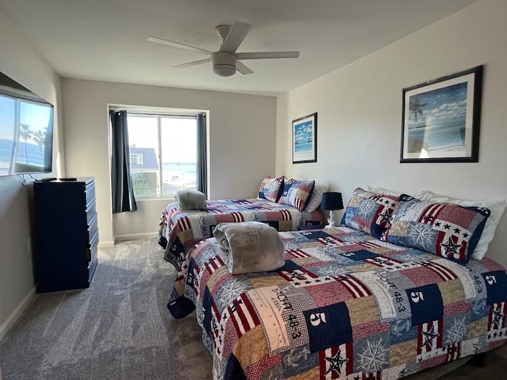 Habitación de invitados en la planta baja con 2 camas matrimoniales y televisión por cable.  El dormitorio tiene un ventilador/lámpara de techo y fabulosas vistas al mar y a la alberca.