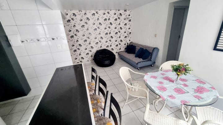 sebule kubwa iliyo na sofa, puf, meza ya viti 4 na jiko la kimarekani 