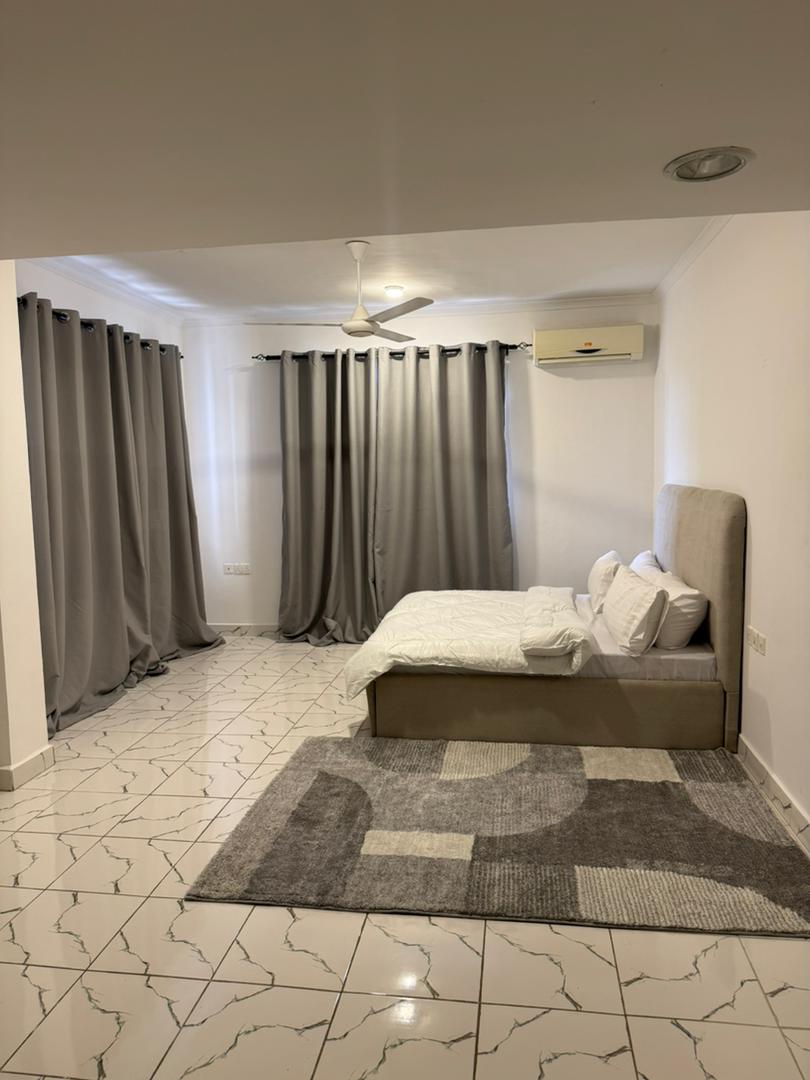 غرفة نوم مشرقة ومريحة مع سرير مريح ومكيف هواء ومروحة سقف ومساحة واسعة للاسترخاء.