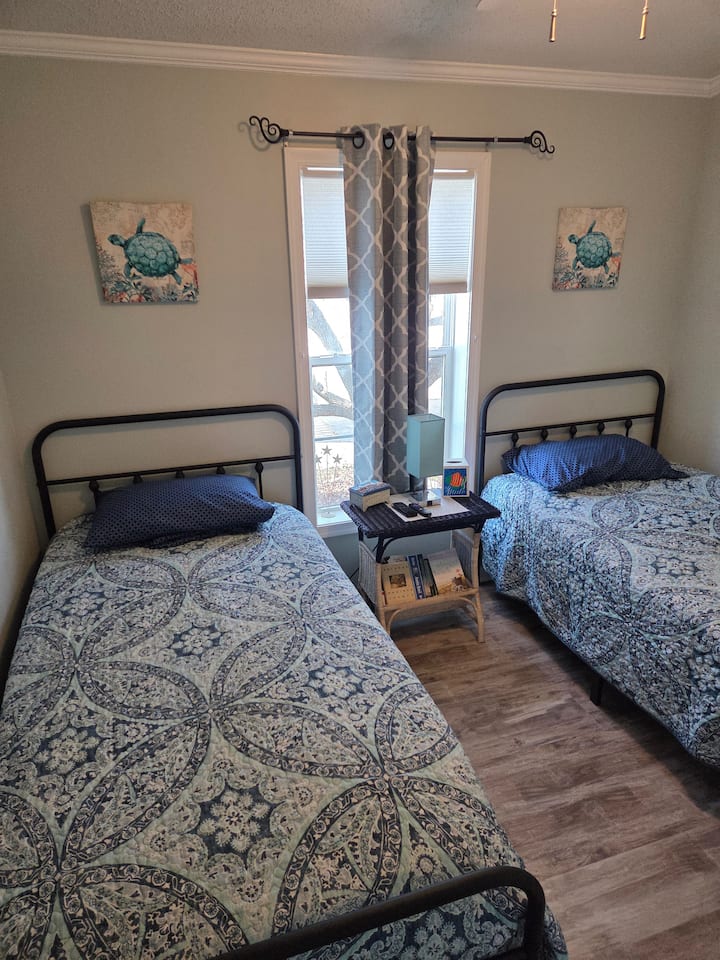 Chumba cha kulala cha wageni vitanda 2 pacha, televisheni iliyowekwa na kabati la nguo.