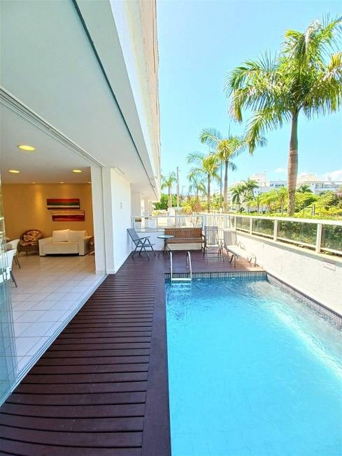 A private balcony features a small pool and wooden decking, surrounded by lush greenery and palm trees. Outdoor furniture is arranged for dining and relaxation, providing a tranquil space to enjoy the surroundings.