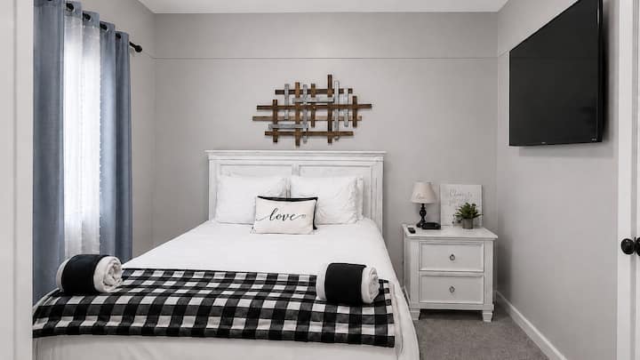 Cozy queen room with TV, plush bedding, and blackout curtains
