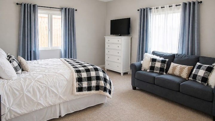 Bright bedroom with sofa seating, TV, and cozy plaid accents