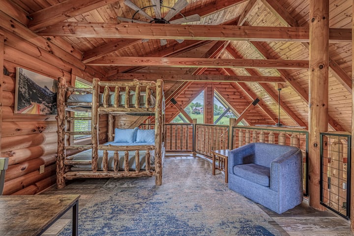 Loft rustique avec lits superposés en rondins, poutres voûtées et vue panoramique par les fenêtres