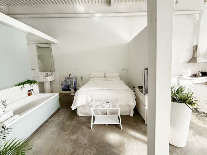 The bed is tucked behind the kitchen wall. Linens are percale cotton sheets, luggage stand for you. Watch tv from the tub or the bed.