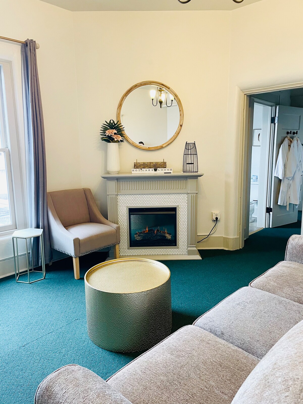 Sitting room of Rm. 217 with electric fireplace and Queen hide a bed. Bedroom #1 is to the left and the Bathroom and Bedroom #2 are located to the right down a short hall. 
