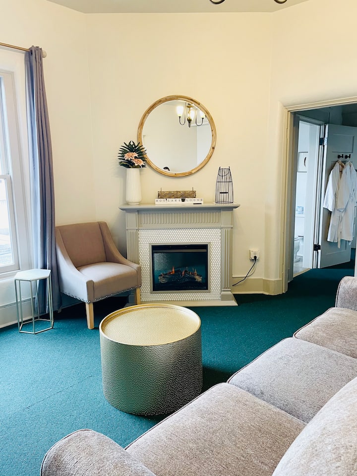 Sitting room of Rm. 217 with electric fireplace and Queen hide a bed. Bedroom #1 is to the left and the Bathroom and Bedroom #2 are located to the right down a short hall. 