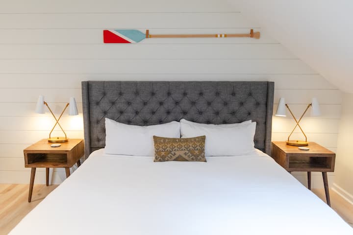 À L'ÉTAGE : Chambre n° 2 / « Lake Suite » : chambre spacieuse à l'étage avec un matelas taille king. Comprend une demi-salle de bain attenante (sans douche), une télévision intelligente et deux fauteuils, ainsi qu'un coin bar avec évier. Veuillez noter que la buanderie est située dans cette chambre.