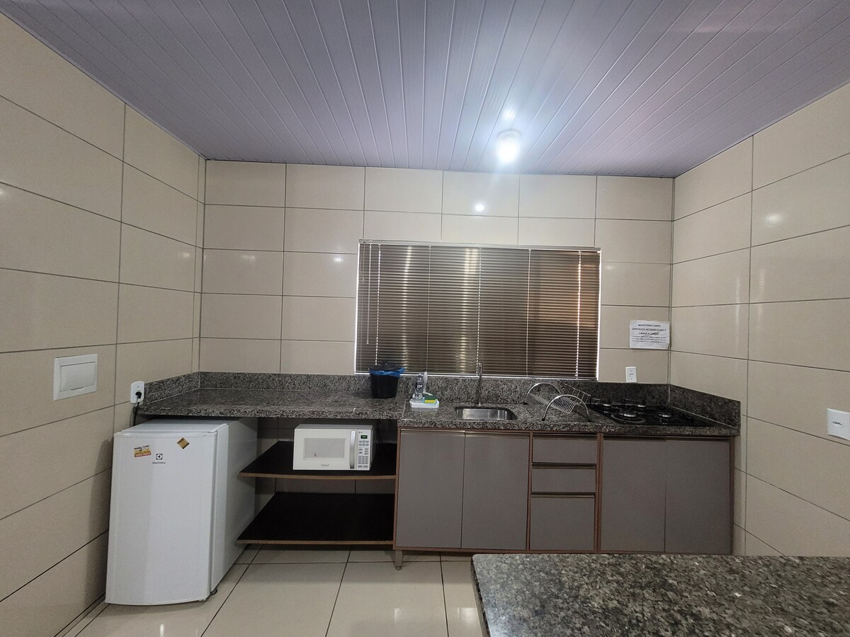 The kitchen area is designed with modern cabinetry and a granite countertop. It includes a microwave, refrigerator, and a gas stove. Natural light enters through a window, illuminating the space while offering a clean and functional layout.
