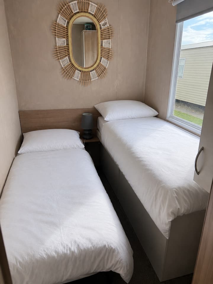 2 single beds.
Small room with 2 single beds, wardrobe with hangers and mirror.
Decorated in textured line wash paint with blind.

*Please note bed is a cabin bed so slightly higher next to window so may not be suitable for small children under 10.