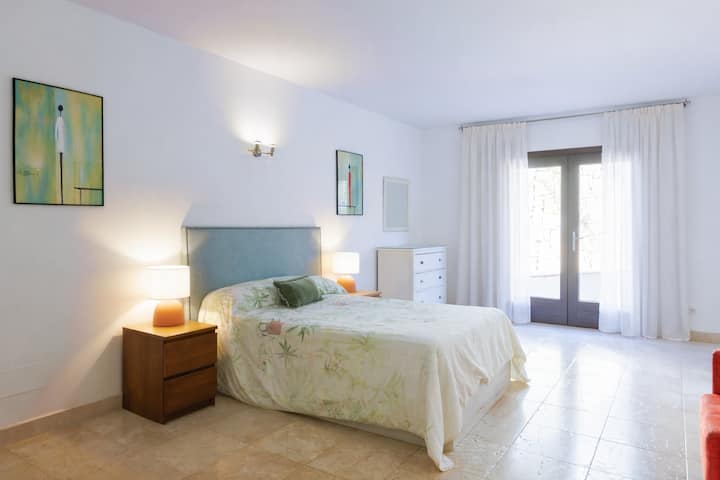 宽敞的卧室，配有大双人床、独立卫生间和外出通道。