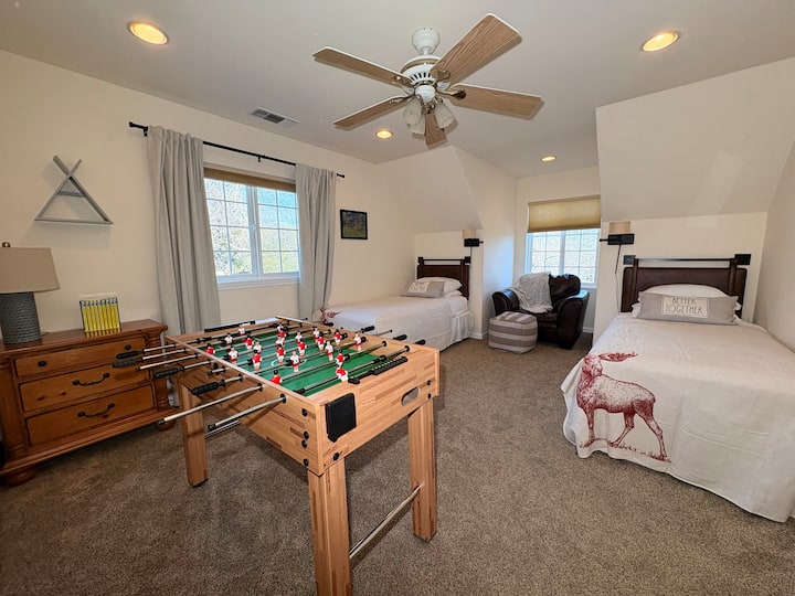 Open views and natural light shape this spring-ready room, where two twin beds offer a restful place to land. Between quiet mornings and casual games at the foosball table, the space feels relaxed, easygoing, and designed for shared stays.