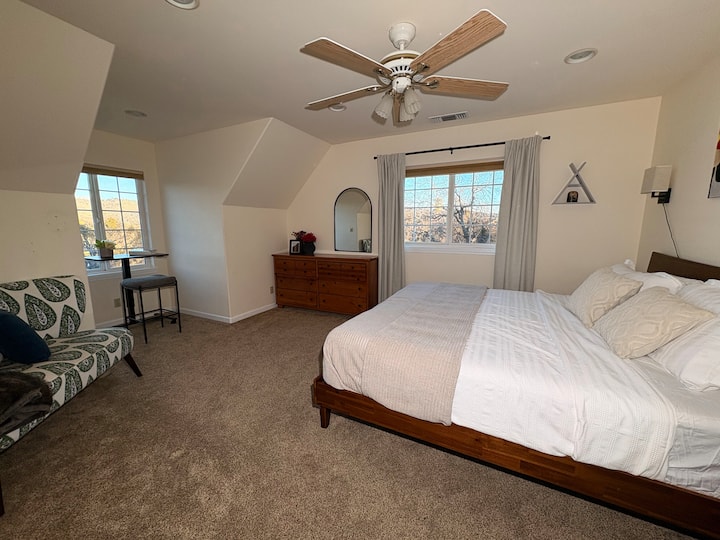  A king-sized bed invites deep rest in the calm mountain retreat that feels open, balanced, and unhurried. Equipped with a sit stand desk set overlooking the mountain range for remote work, comfy seating, storage, blackout curtains, fan for comfort.