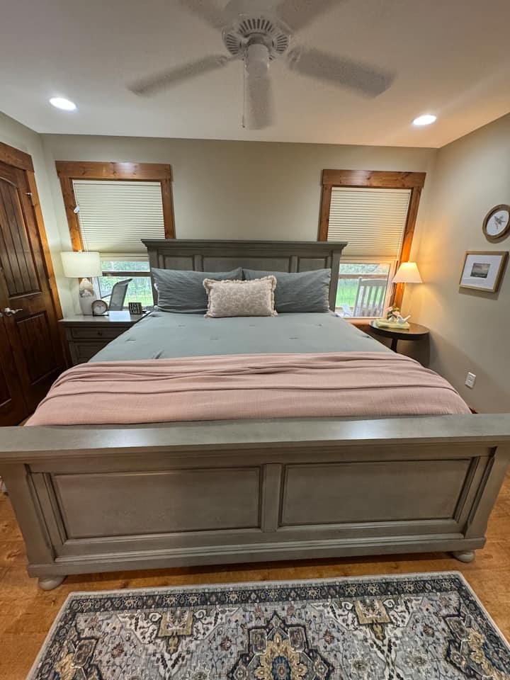 חדר שינה ראשי בקומה הראשית עם מיטת קינג סייז, טלוויזיה חכמה, חדר ארונות וחדר רחצה מלא. 