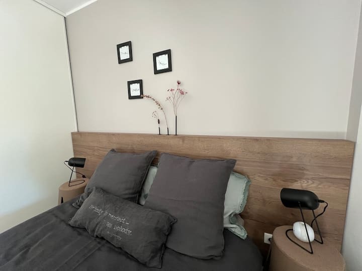 Jolie tête de lit avec table et lampe de chevet de chaque côté du lit