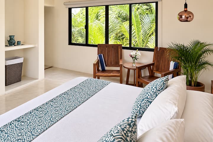Chambre à l'étage supérieur, avec vue partielle sur la lagune et le jardin. La chambre dispose d'un lit king size et d'une salle de bain privée.